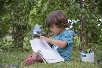 Young woman reading book while sitting outdoors