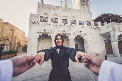 Cropped image of man holding woman hands in town