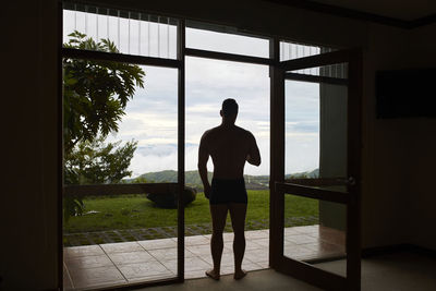 Rear view of man looking through window