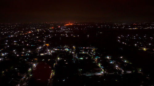 Illuminated cityscape against sky at night