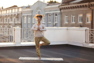 Full length of young woman standing against building