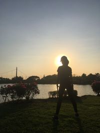 Silhouette man standing on shore against sky during sunset