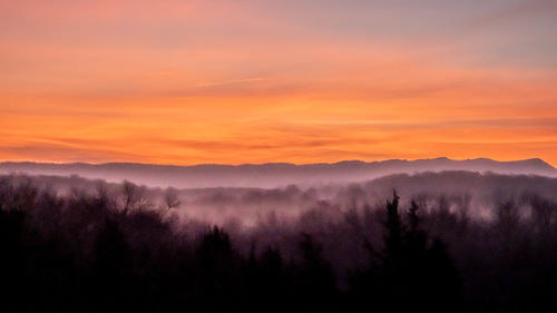 Scenic view of silhouette mountains against orange sky