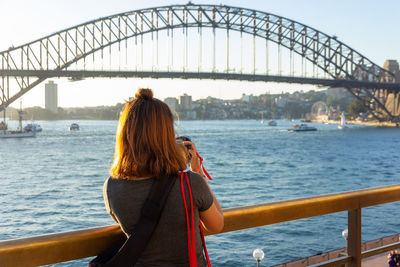 Rear view of woman standing against railing on bridge