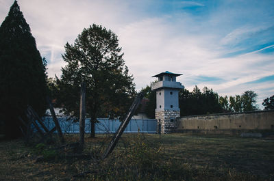 Built structure on field by trees against sky