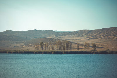 Scenic view of lake by mountains against clear sky