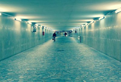 Rear view of man walking in illuminated corridor