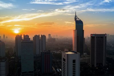 Modern buildings in city against sky during sunset