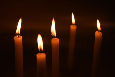 Close-up of lit candles in darkroom