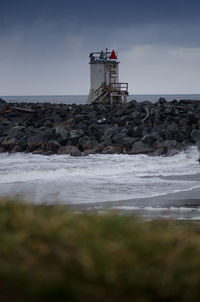 Lighthouse by sea against sky
