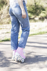 Woman's legs in jeans and pink roller skates in a park