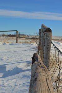 Chainlink fence by wooden post on snowy field in winter