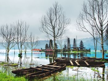 Wooden posts in lake against sky