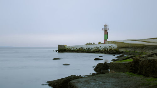 Lighthouse by sea against sky