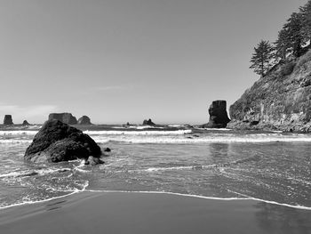 Rock formation in sea against clear sky