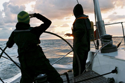 Men standing on boat sailing in sea against sky