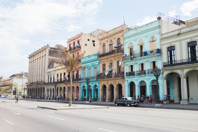 Road by buildings in city against sky