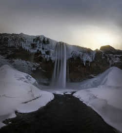 Scenic view of waterfall against sky during winter