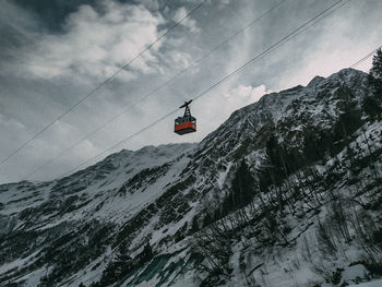 Overhead cable car on snowcapped mountains against sky