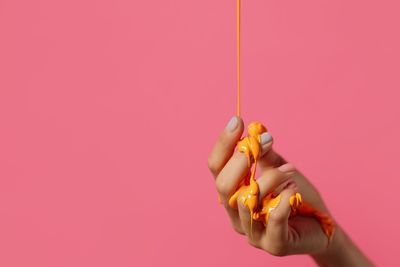 Close-up of hand holding ice cream against pink background