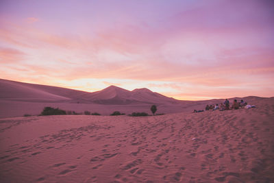 Scenic view of desert and people at sunset