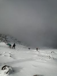 People on snow covered land against sky