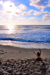 Rear view of person on beach against sky during sunset