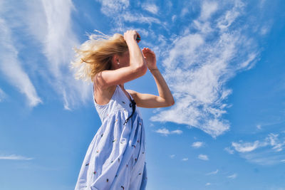 Low section of woman standing against blue sky