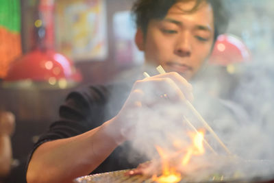 Man picking food with chopsticks in restaurant