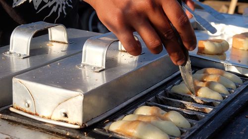 Cropped hands of vendor preparing food at market stall