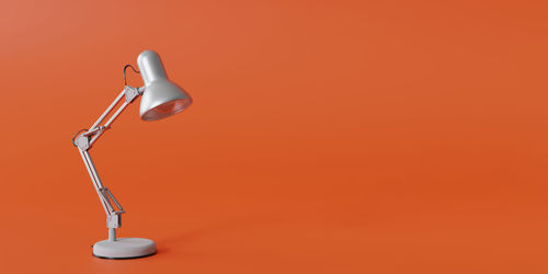 Close-up of electric lamp against orange wall