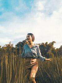 Young woman looking away while standing on land against sky