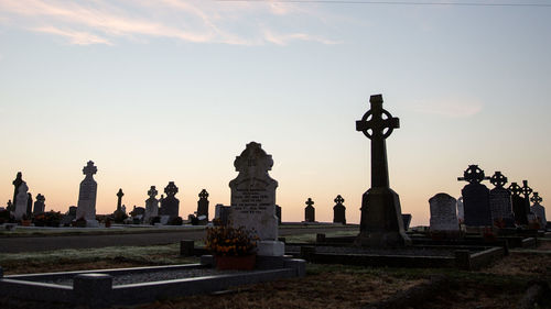 Statue in cemetery against sky during sunset