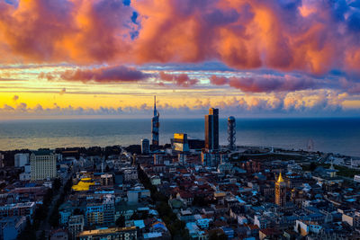 High angle view of buildings by sea against sky during sunset