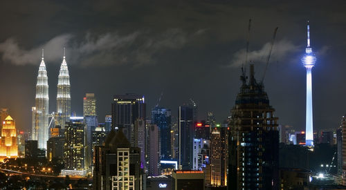 Illuminated petronas towers and kuala lumpur tower in city at night