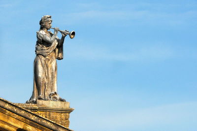 Low angle view of statue against blue sky