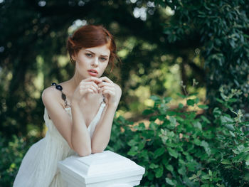 Portrait of young woman against plants