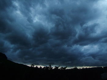 Low angle view of dramatic sky over silhouette landscape