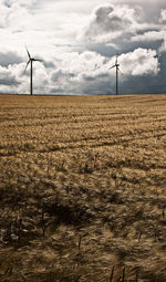 Wind turbines on field against sky