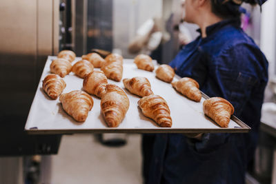 Midsection of woman holding food in tray at bakery