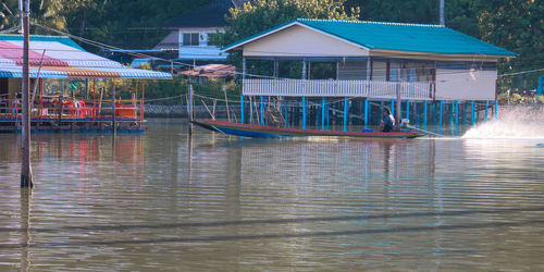 Boats moored in lake by houses against buildings