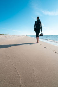 Rear view of man on beach against sky