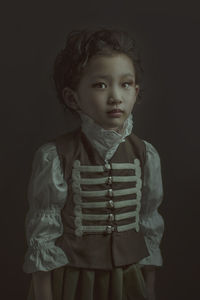 Cute girl looking away while standing against black background