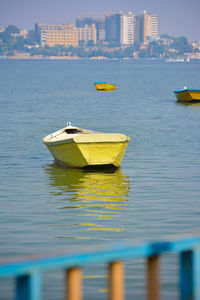 Sailboats moored on sea by buildings in city