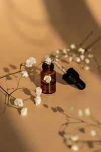 Small bottle of serum on neutral beige background. beauty pipette dropper with gypsophila or baby's