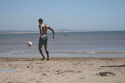 Full length of man playing with ball on beach