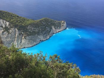 Close-up of sea and trees against blue sky