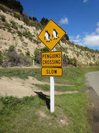 Information sign on road by mountain against sky