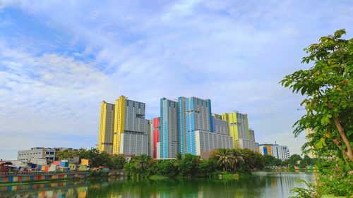 Modern buildings by river against sky