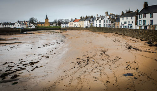 Buildings by sandy beach against sky